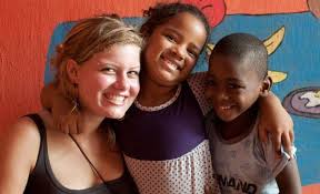 una giovane volontaria con due bambini di colore